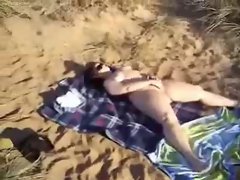 Horny slut at beach masturbating for voyeurs